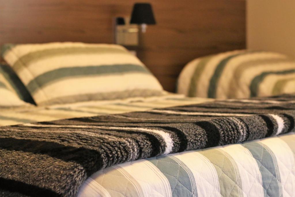 duas camas com almofadas listradas sentadas uma ao lado da outra em Stefano Hotel em São Roque