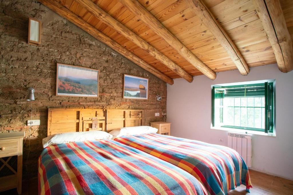 1 dormitorio con 1 cama con una manta colorida en Casa de los Curas, chimenea 2 Hab 4 Pers Max, en Puerto de la Laja