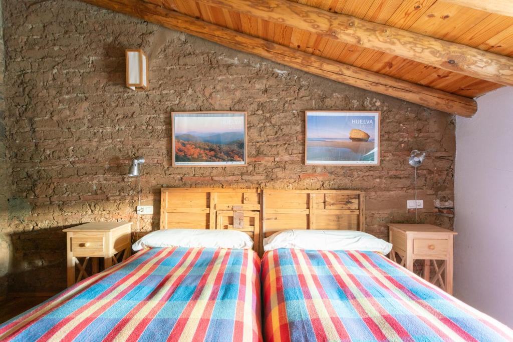 Dos camas en una habitación con pared de piedra. en Casa de los Curas, chimenea 2 Hab 4 Pers Max, en Puerto de la Laja