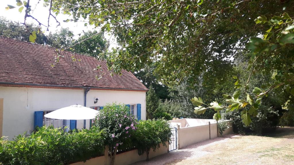 una casa blanca con una valla y una sombrilla en Le Coeur Du Moulin, en Saint-Aubin-le-Monial