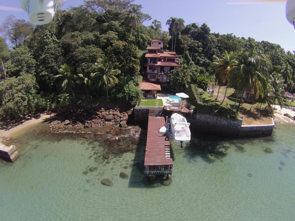 un molo con una barca in acqua accanto a una casa di CASA MARAVILHOSA à BEIRA MAR EM ANGRA DOS REIS ad Angra dos Reis