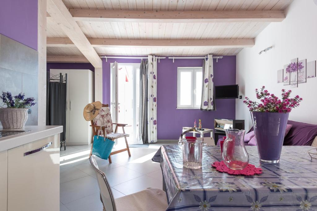 eine Küche mit lila Wänden und einem Tisch mit Blumen darauf in der Unterkunft Casa Zefiro in Pozzallo