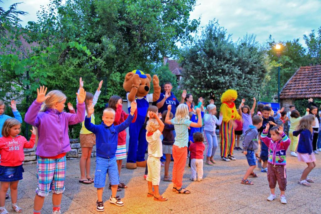 um grupo de crianças de pé em uma multidão com as mãos para cima em Domaine de La Paille Basse em Souillac