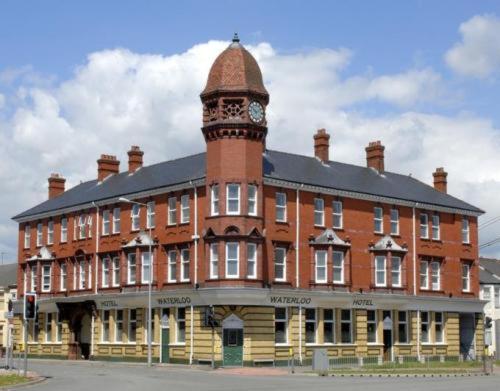 a large brick building with a clock tower on top at The Waterloo Hotel & Bistro in Newport
