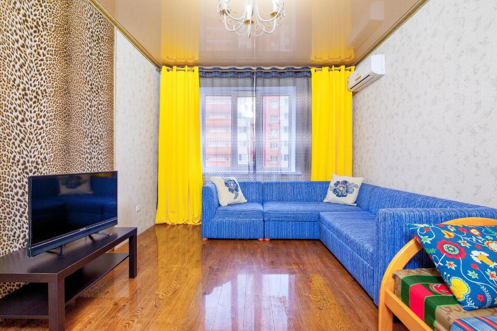 ein Wohnzimmer mit einem blauen Sofa und einem TV in der Unterkunft Panorama 22/2 in Krasnodar