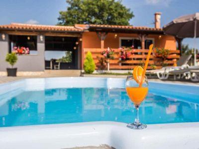 un bicchiere di succo d'arancia seduto sul bordo della piscina di Romantic Villa Sejdić a Pola (Pula)