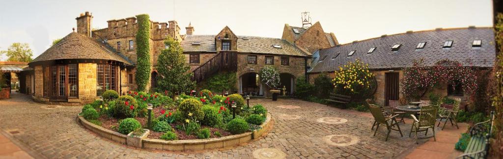a large house with a garden with flowers in it at Alnwick Lodge West Cawledge Park in Shilbottle