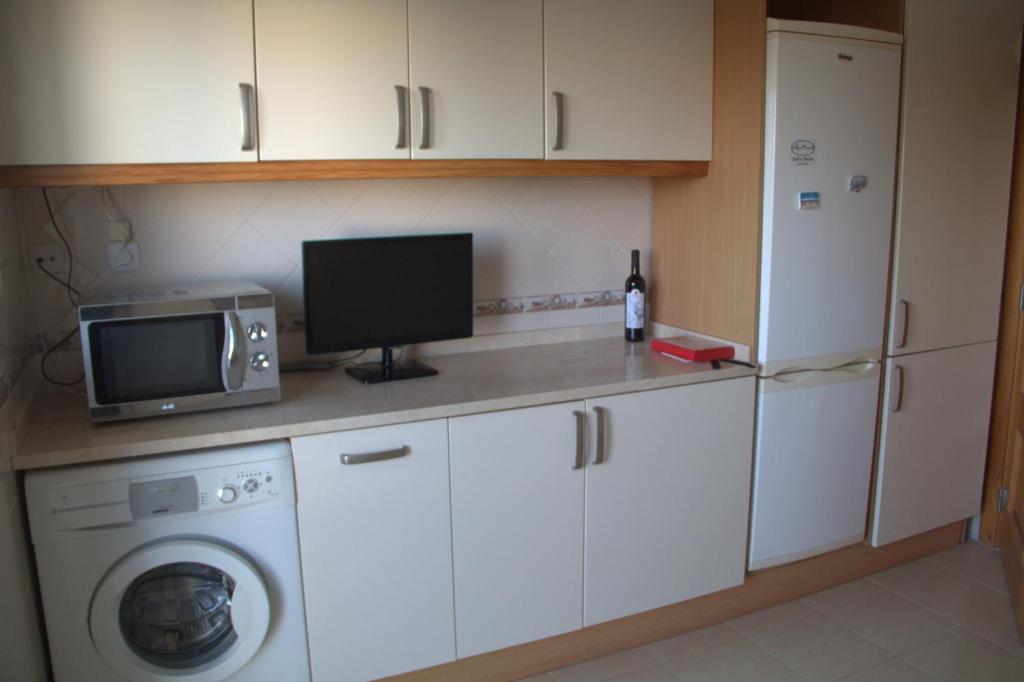 a kitchen with a washing machine and a tv at Ericeira Sunset Apartment in Ericeira