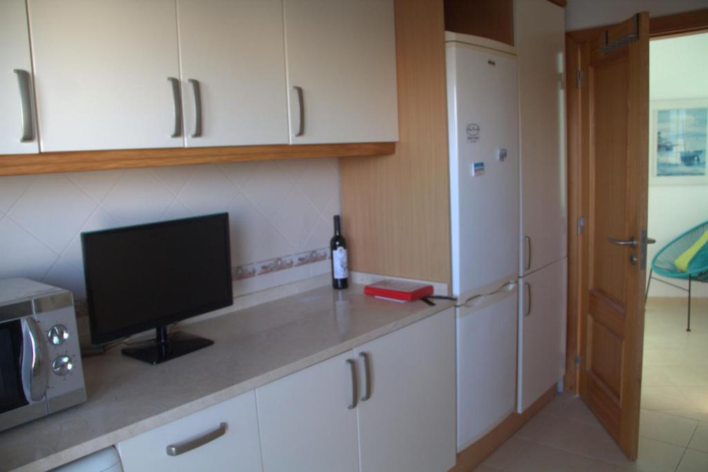 a kitchen with white cabinets and a television on a counter at Ericeira Sunset Apartment in Ericeira