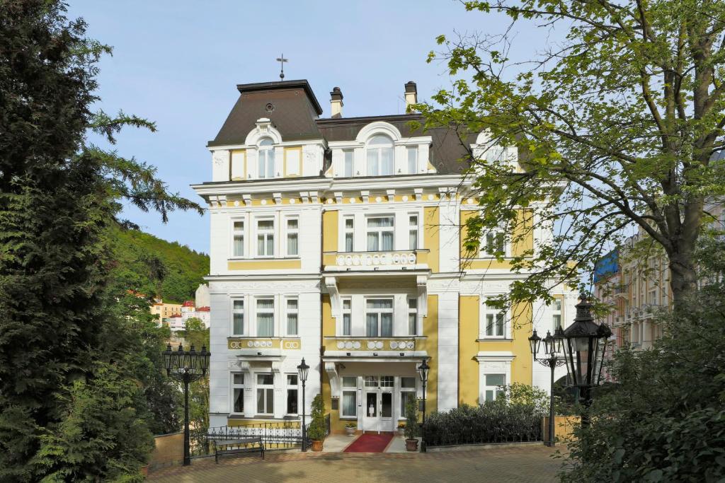 un edificio blanco y amarillo con techo en Hotel Vila Livia, en Karlovy Vary