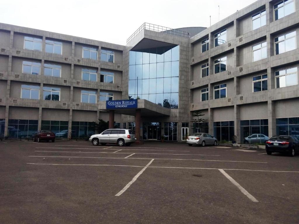 un estacionamiento con autos estacionados frente a un edificio en Golden Royale Hotel, en Enugu