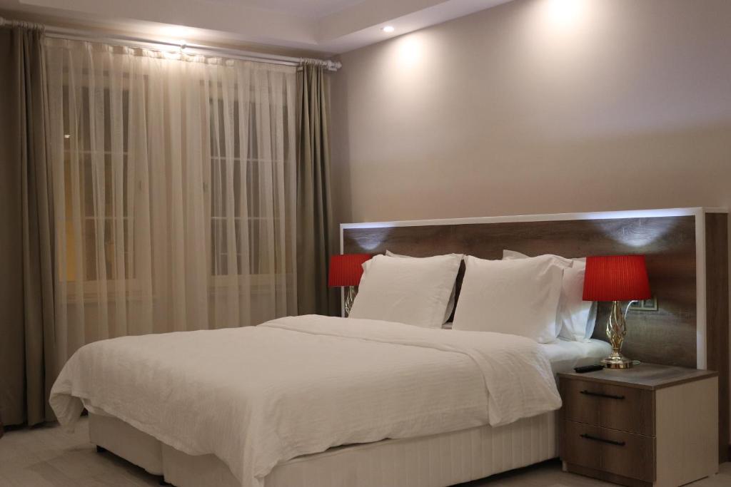 a bedroom with a large bed with white sheets and red lamps at Yankı Hotel in Çekirge