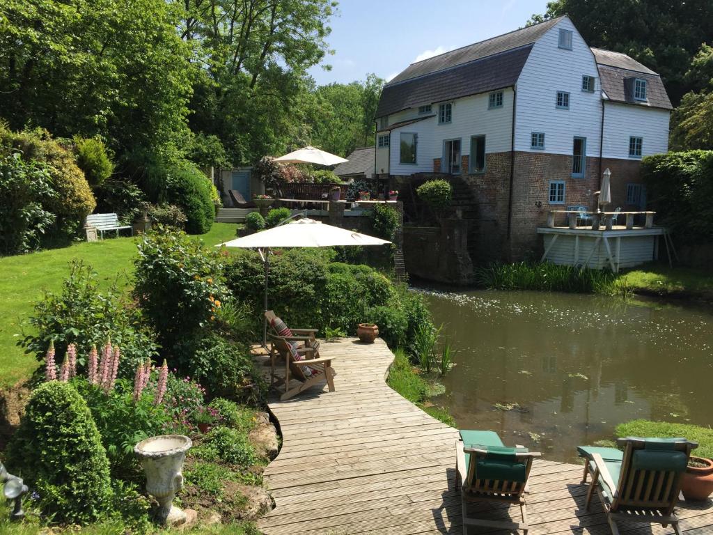 einen Holzsteg neben einem Teich mit einem Haus in der Unterkunft Castle Mill Bed and Breakfast in Dorking