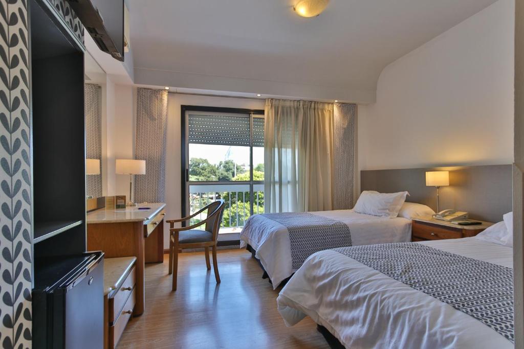 een hotelkamer met 2 bedden, een bureau en een raam bij Gran Hotel Parana in Paraná