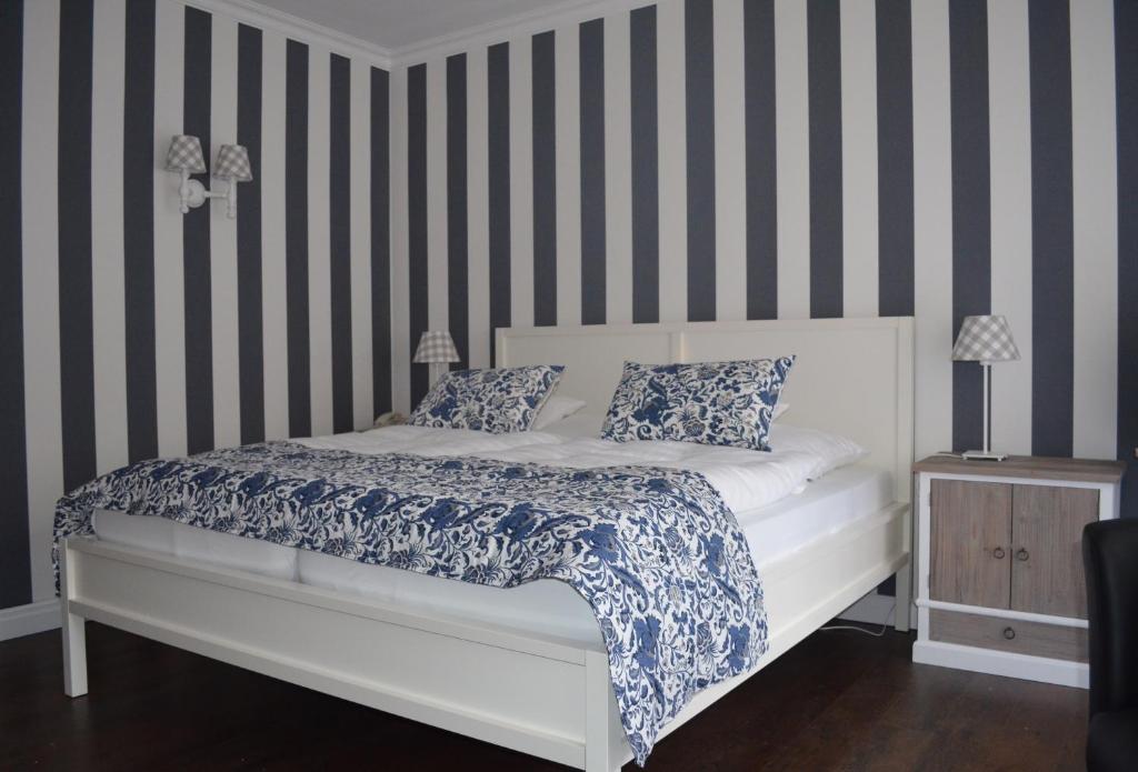 a bedroom with a white bed with striped walls at Heide´s Hotel Pension Bad Bevensen in Bad Bevensen