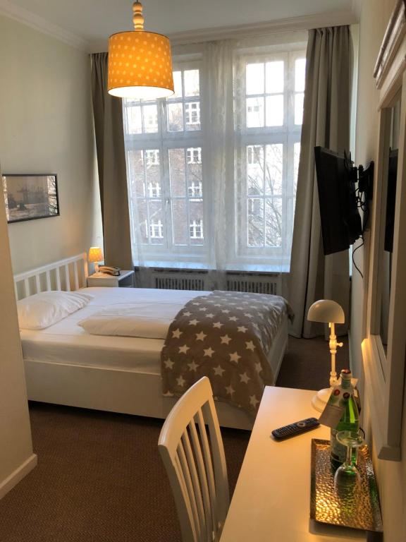 a bedroom with a bed and a window and a table at Hotel Fresena im Dammtorpalais in Hamburg