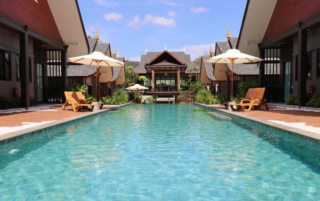 a swimming pool with chairs and umbrellas next to a building at The Scene Cliff View Villas in Ao Nang Beach