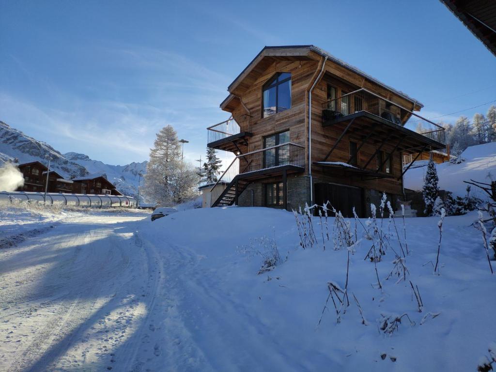 a log cabin in the snow with a road in front at Le Chalet des Boisses, Luxury Ski-In Ski-Out Chalet for 12 in Tignes