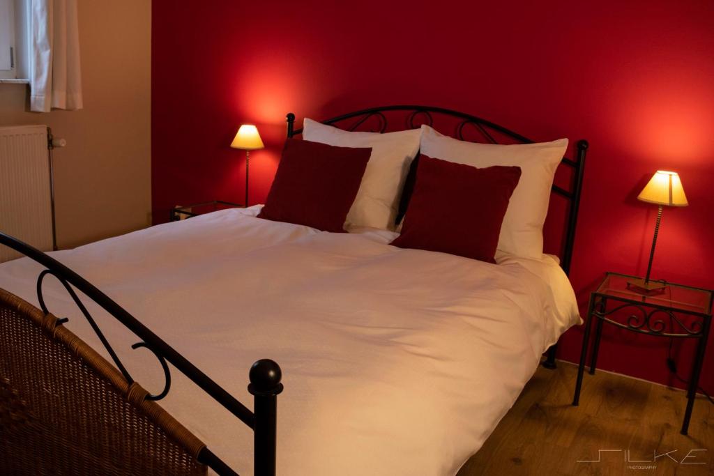 een slaapkamer met een groot bed met rode muren bij De Loteling in Zoersel