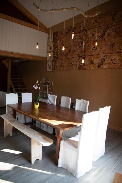 a wooden table and white chairs in a room at Le Chat Blanc in Versols-et-Lapeyre