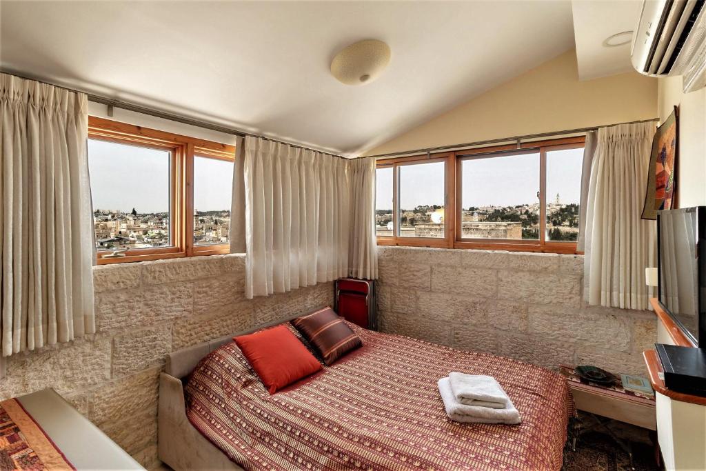 Schlafzimmer mit einem Bett mit roten Kissen und Fenstern in der Unterkunft Into Jerusalem heart in Jerusalem