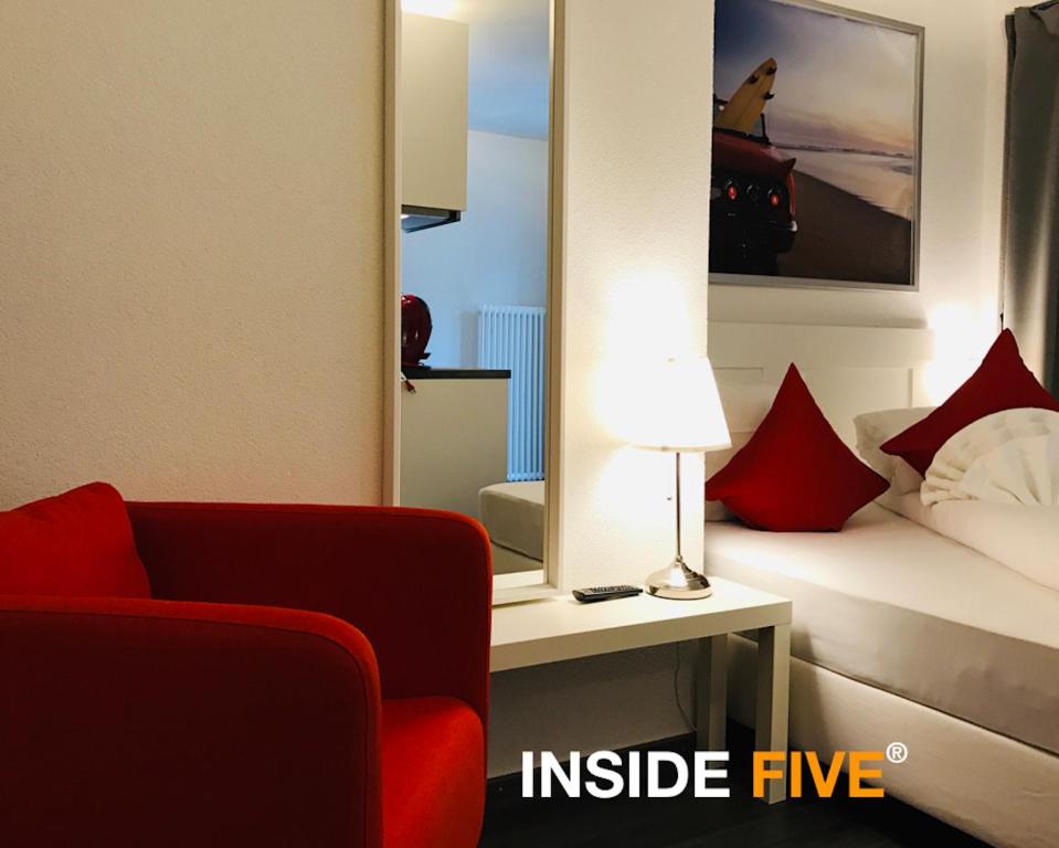 a room with a red chair and a bed with a mirror at INSIDE Five in Zürich