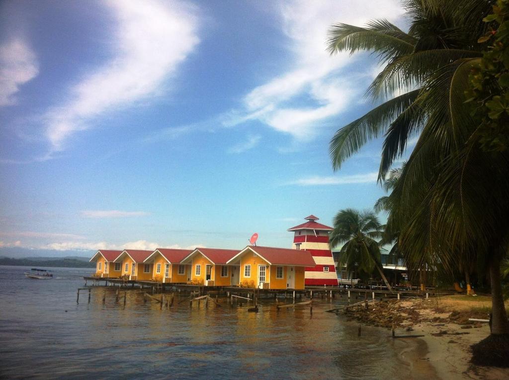 
a beach scene with boats and a lighthouse at Faro del Colibri in Bocas del Toro
