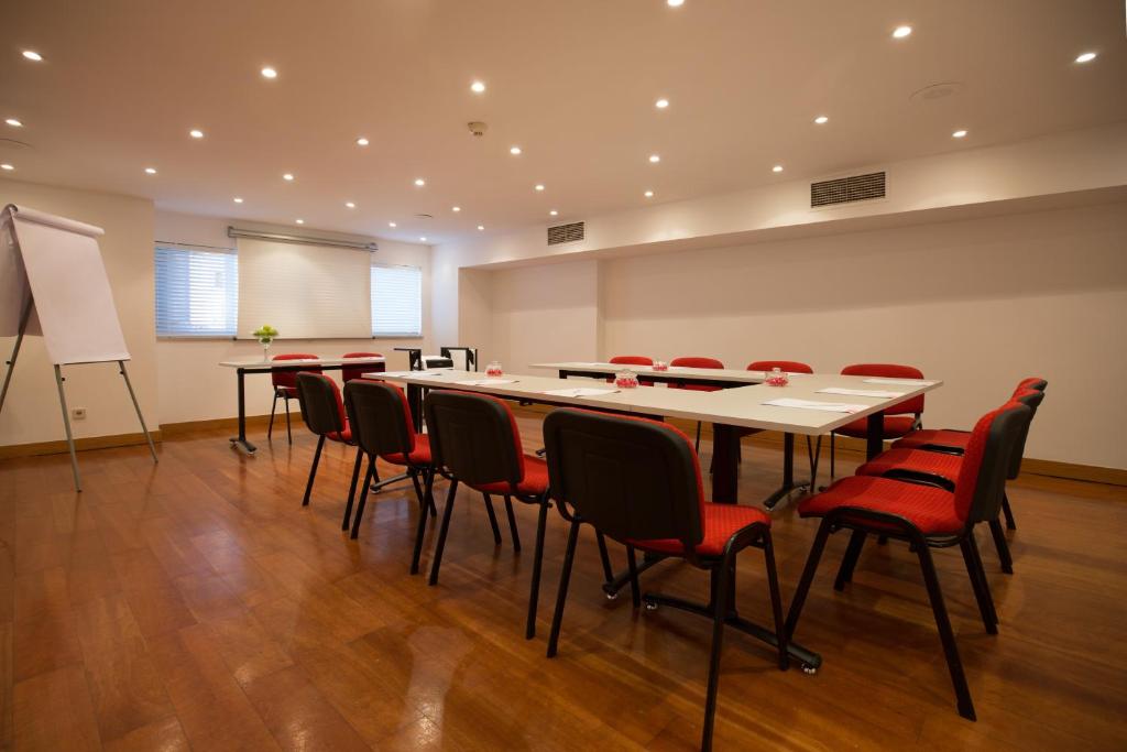 a conference room with a table and red chairs at Legendary Porto Hotel in Porto