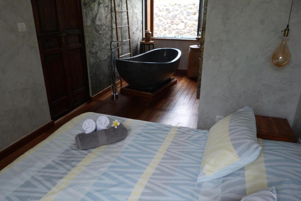 a bedroom with a tub and a bed with two towels at L'Orée du Maïdo in Le Guillaume