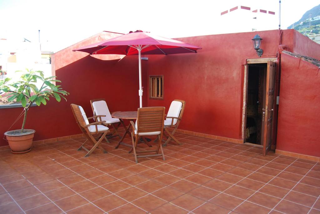 un patio con mesa, sillas y sombrilla en LA CASITA DEL MUELLE, en Garachico