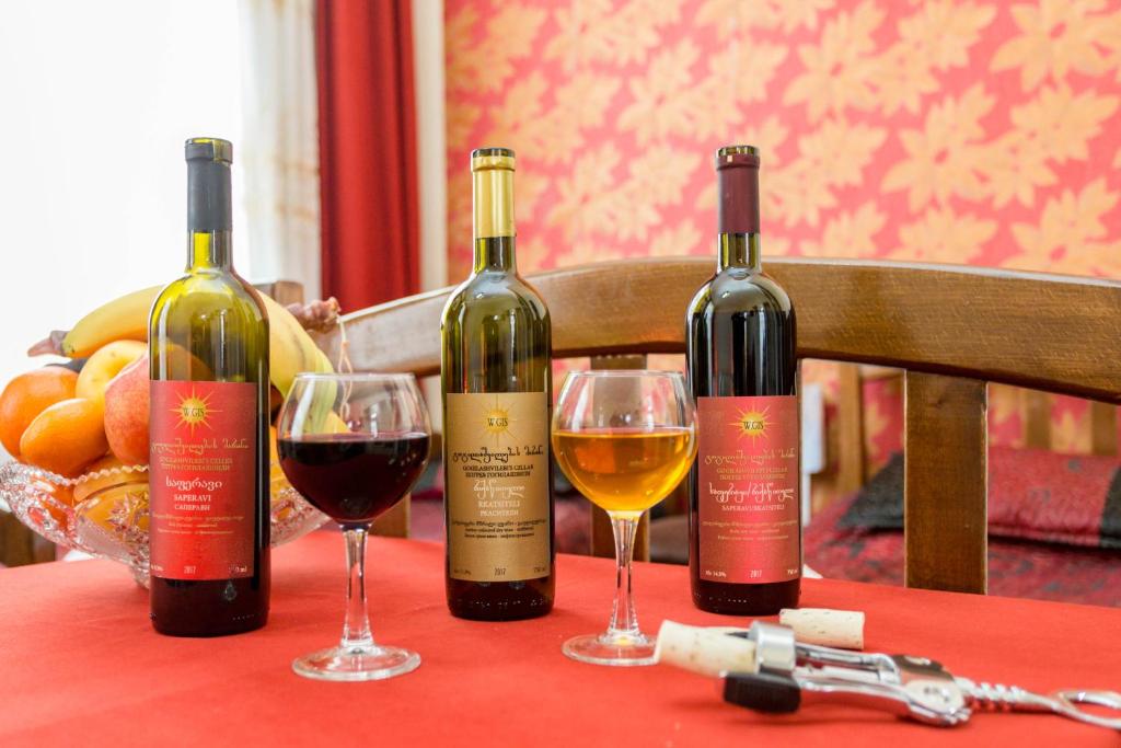 トビリシにあるGis Guest Houseのワイングラス付きのテーブルに座ったワイン3本
