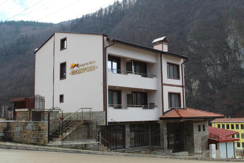 ein großes weißes Gebäude mit einem Berg im Hintergrund in der Unterkunft Къща за гости Мишурови in Smoljan