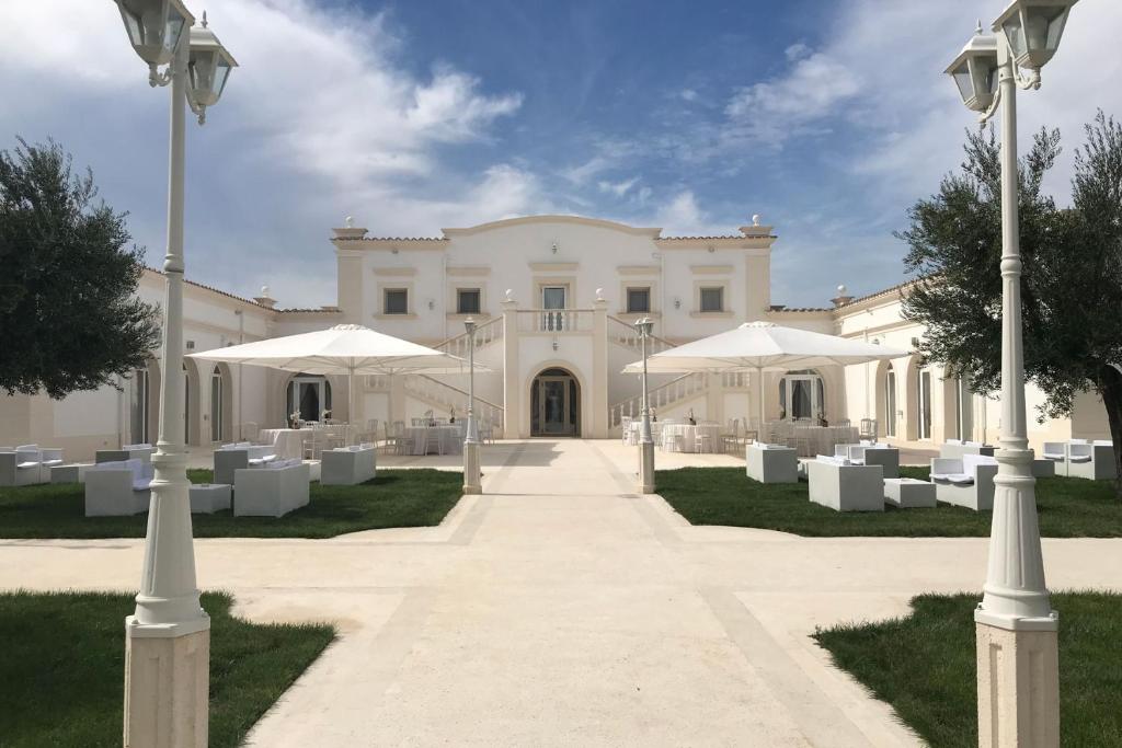 a large white building with white tables and umbrellas at La Magione in Foggia