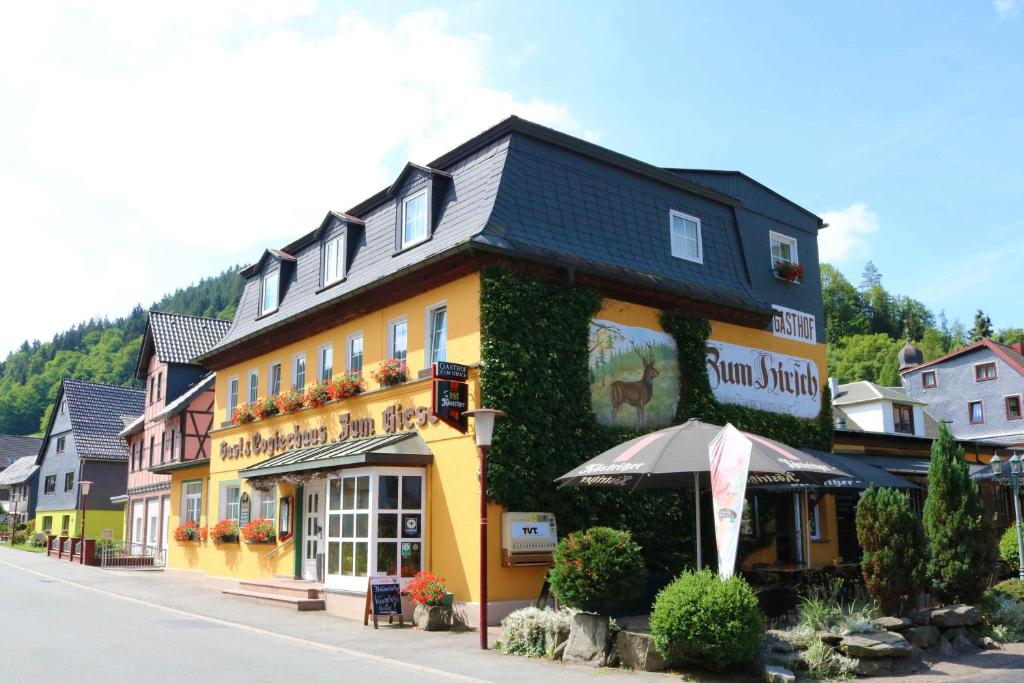 ein gelbes Gebäude mit einem Regenschirm auf einer Straße in der Unterkunft Landhotel Zum Hirsch in Unterweißbach