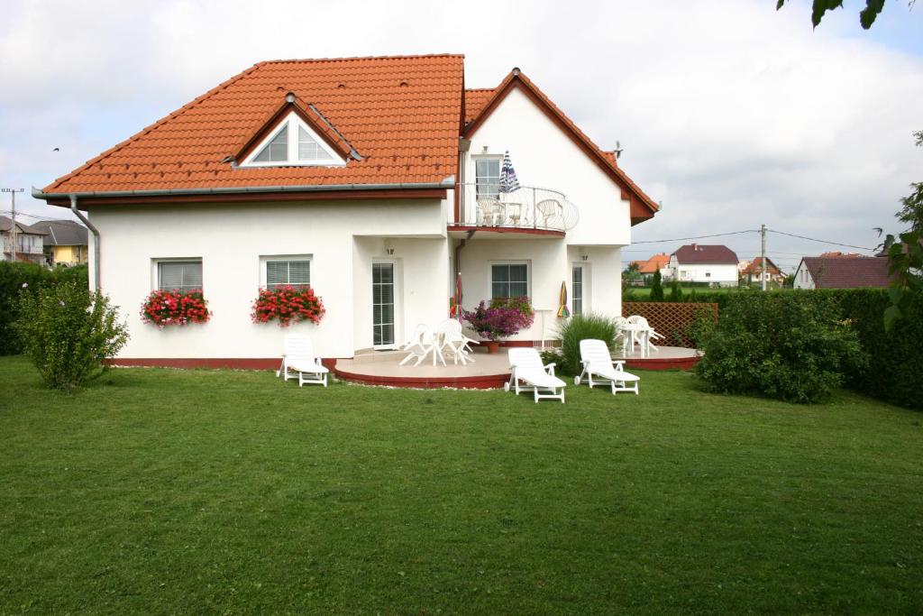 a white house with white chairs in a yard at Doina Apartman in Zalakaros