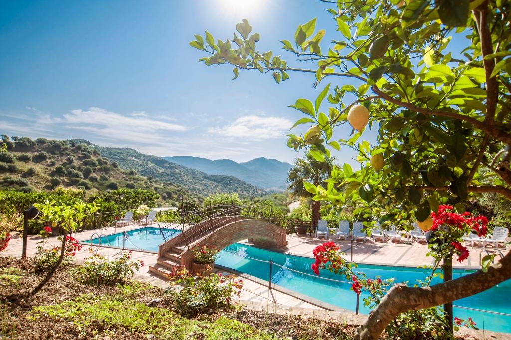 a resort with a swimming pool and mountains in the background at Azienda Agrituristica Bergi in Castelbuono