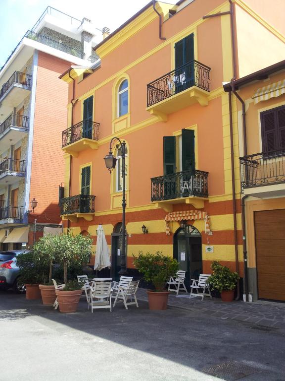 a yellow building with tables and chairs in front of it at Hotel Mimosa in Alassio