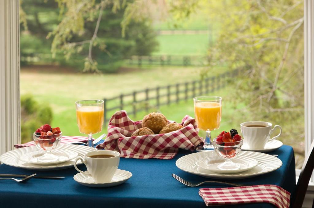 una mesa con platos de comida y bebida y una ventana en The Inn at Whitewing Farm, en West Chester