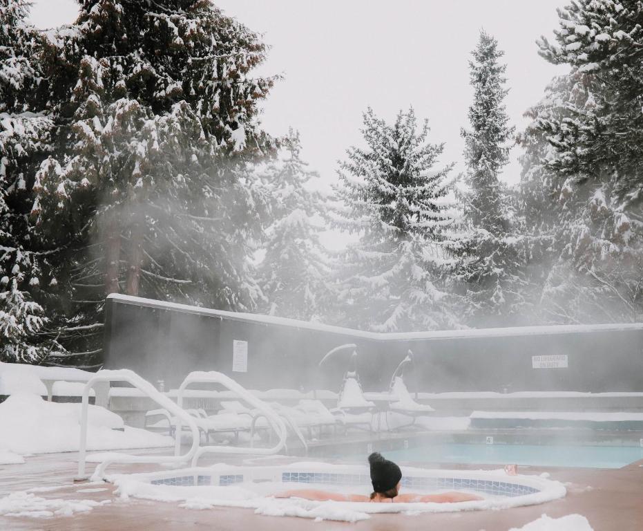 a person sitting in a hot tub in the snow at Adara Hotel in Whistler