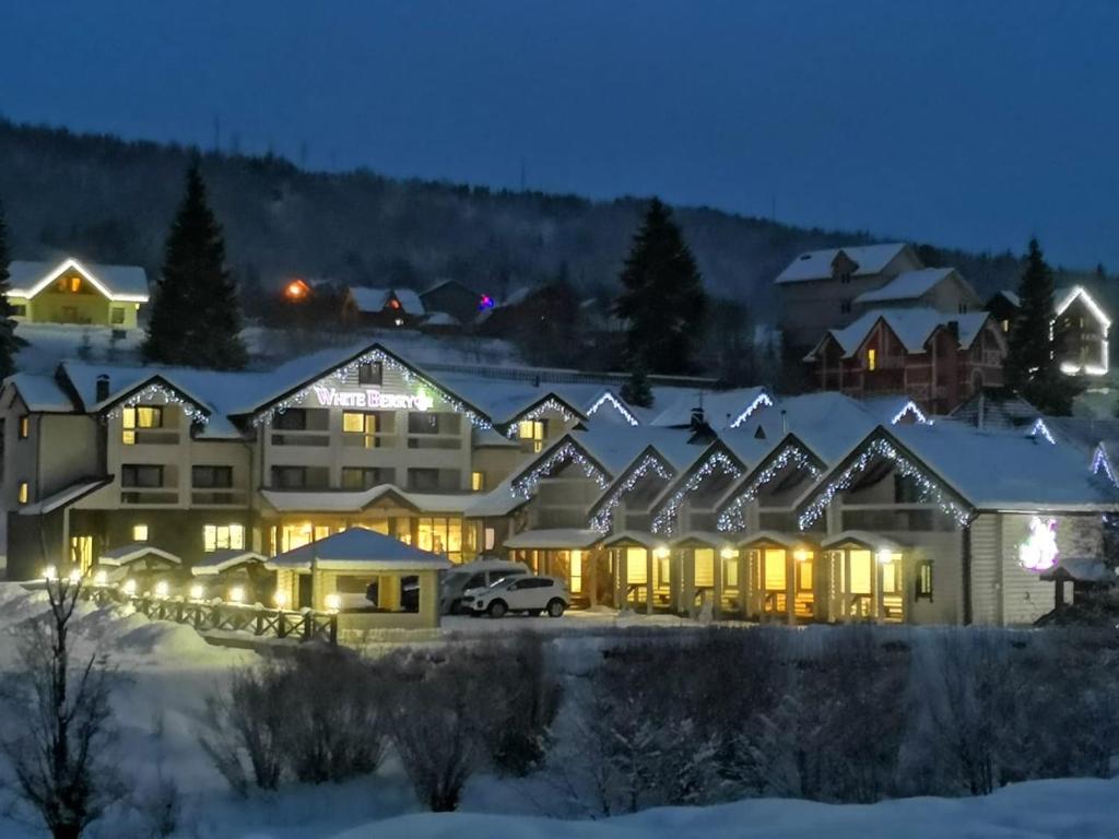 een groot gebouw in de sneeuw 's nachts bij Whiteberry hotel in Boekovel