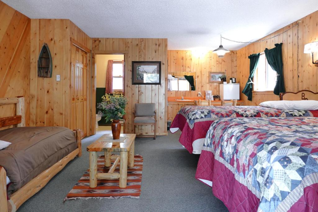 una habitación de hotel con 2 camas y una silla en Bill Cody Ranch, en Cody