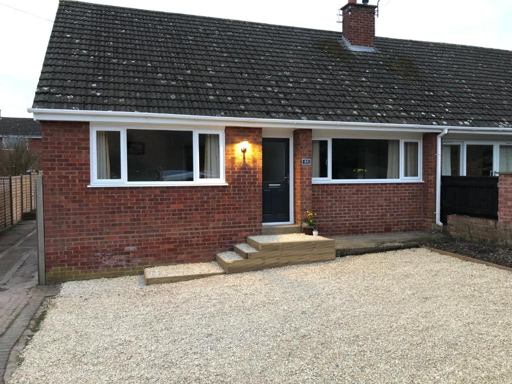 una casa de ladrillo rojo con una puerta y ventanas negras en Malvern bungalow en Great Malvern