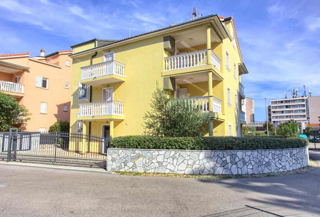a yellow building with white balconies on a street at Baška Point in Baška