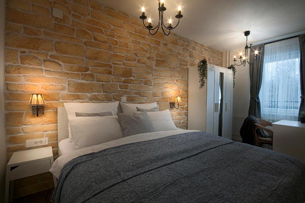 Schlafzimmer mit Ziegelwand und großem Bett in der Unterkunft L&L Leisure Apartments Plitvice in Plitvička Jezera