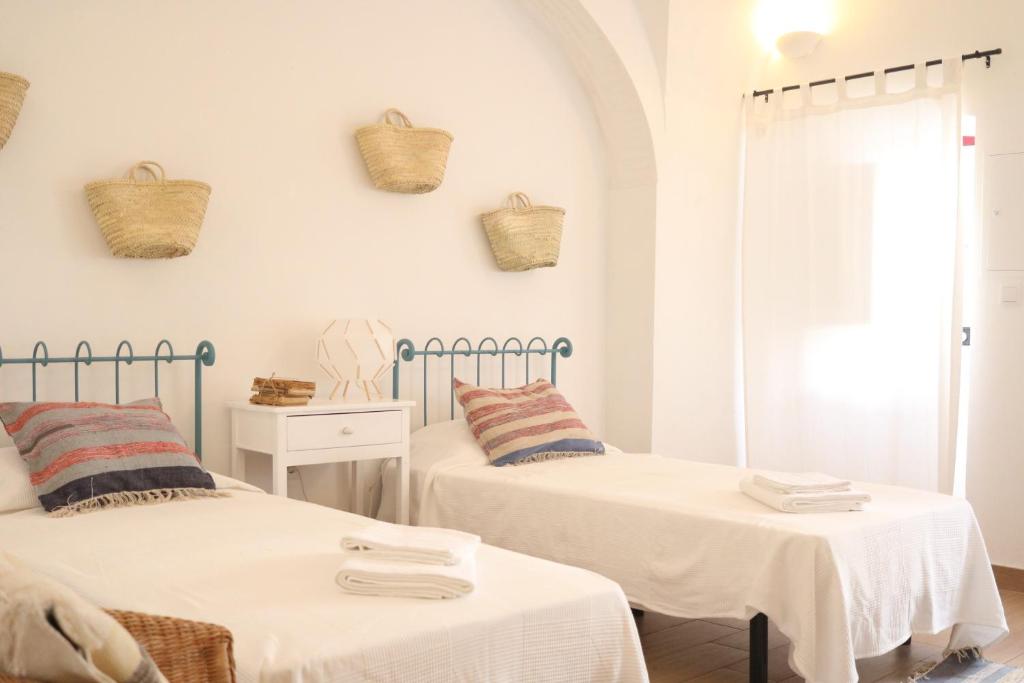 two beds in a white room with baskets on the wall at Casa Centro Histórico Beja - Castelo in Beja