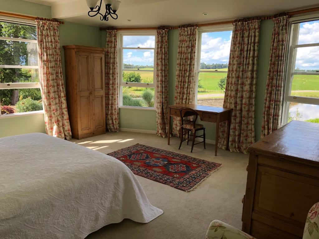 een slaapkamer met een bed, een bureau en ramen bij Te Kopura Lodge in Martinborough 
