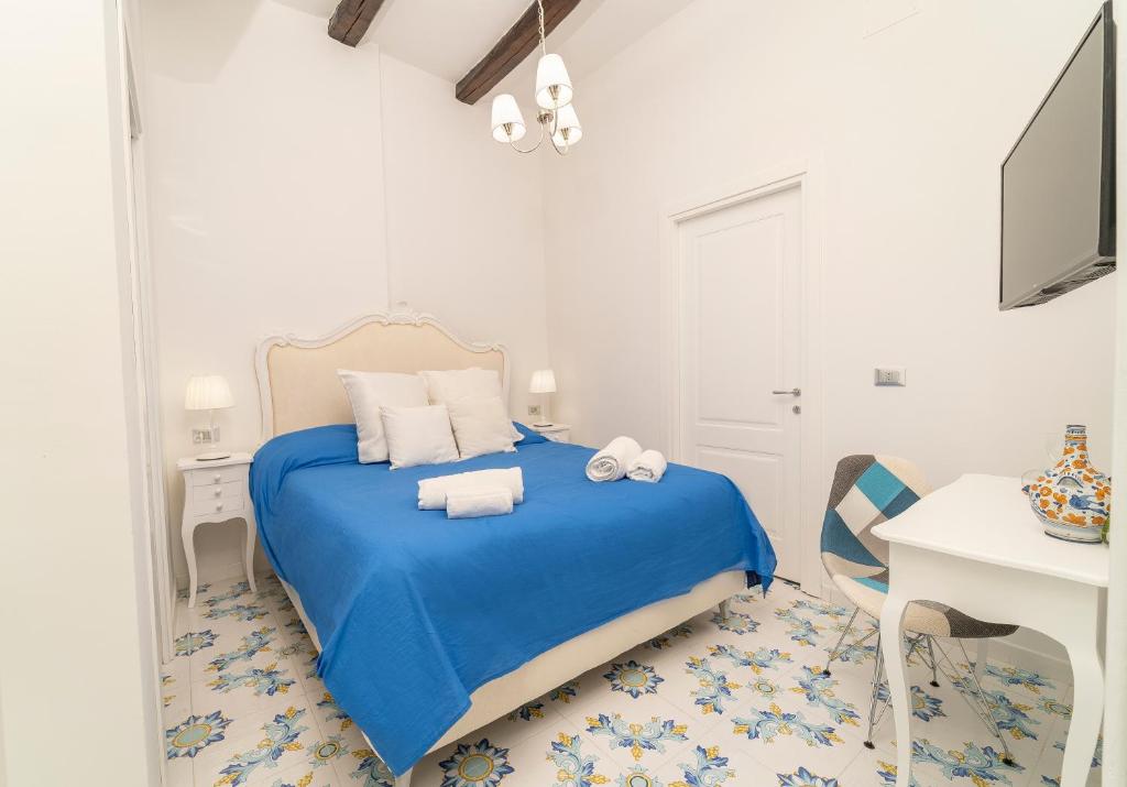- une chambre blanche avec un lit bleu et un bureau dans l'établissement NapulitanDream, à Naples