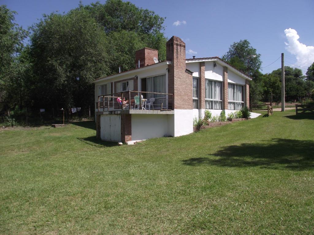 a house on a grassy hill with a large yard at Cina Cina, Chalet de montaña, Icho Cruz Sierra. in Cordoba