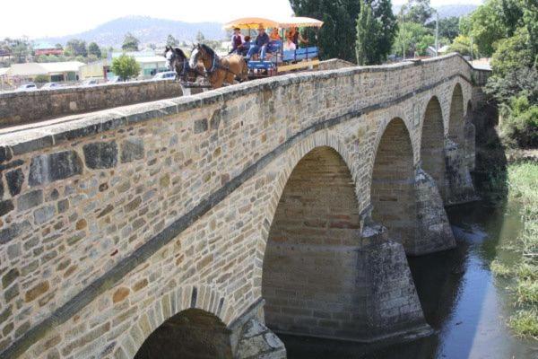 a stone bridge with a horse drawn carriage on at Glamping Gypsy Hobart in Richmond