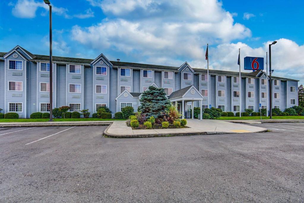 un gran edificio blanco con un árbol de Navidad en un estacionamiento en Motel 6-Sutherlin, OR en Sutherlin